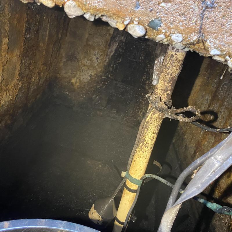 Septic tank interior with float and rusted pipe