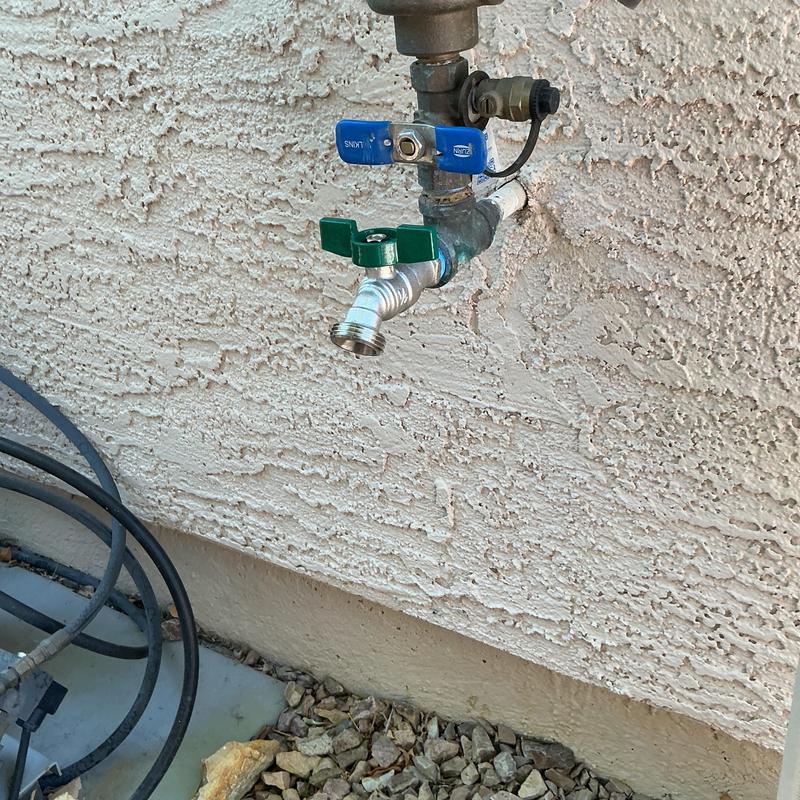 Outdoor hose bib with green handle on stucco wall Outdoor hose bib with green handle on stucco wall