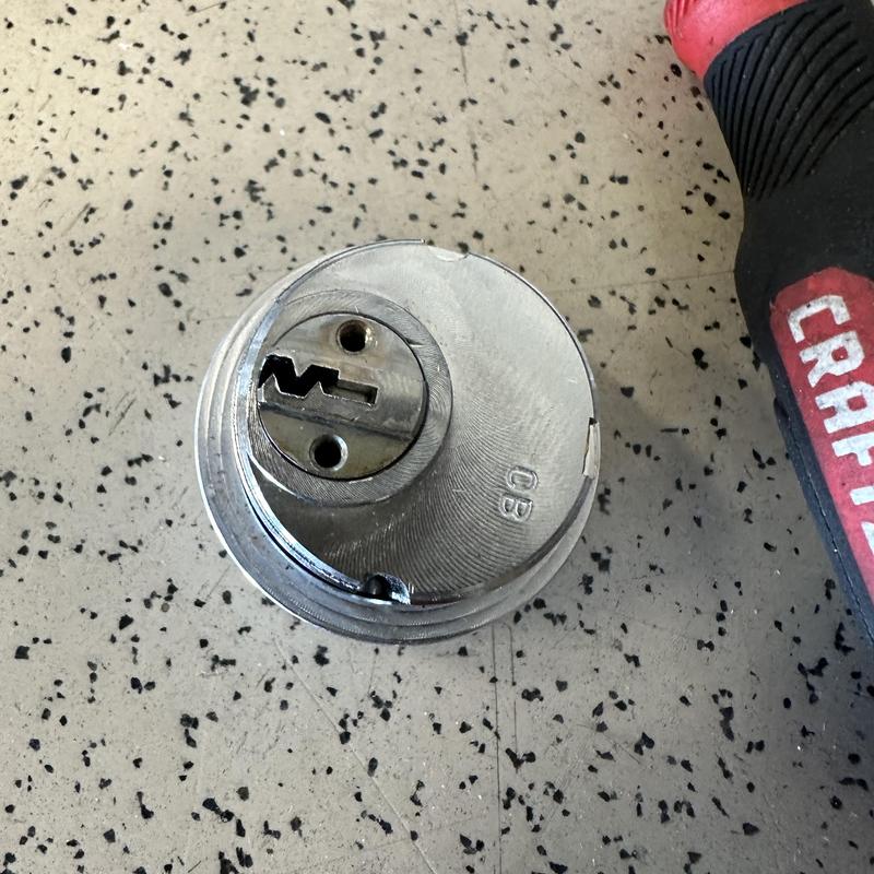 Lock cylinder on workbench next to screwdriver