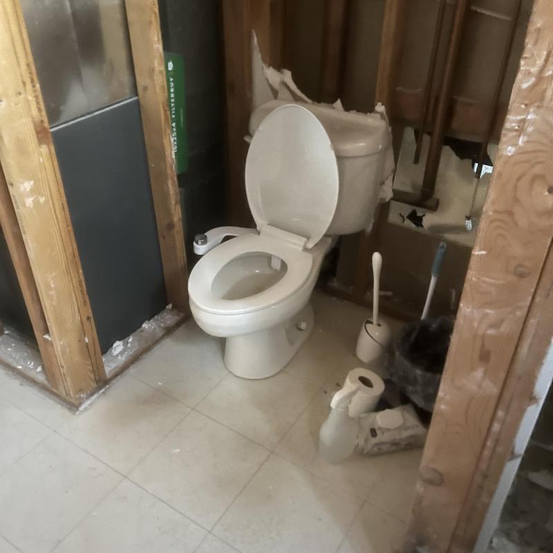 Toilet and exposed plumbing in bathroom remodel site