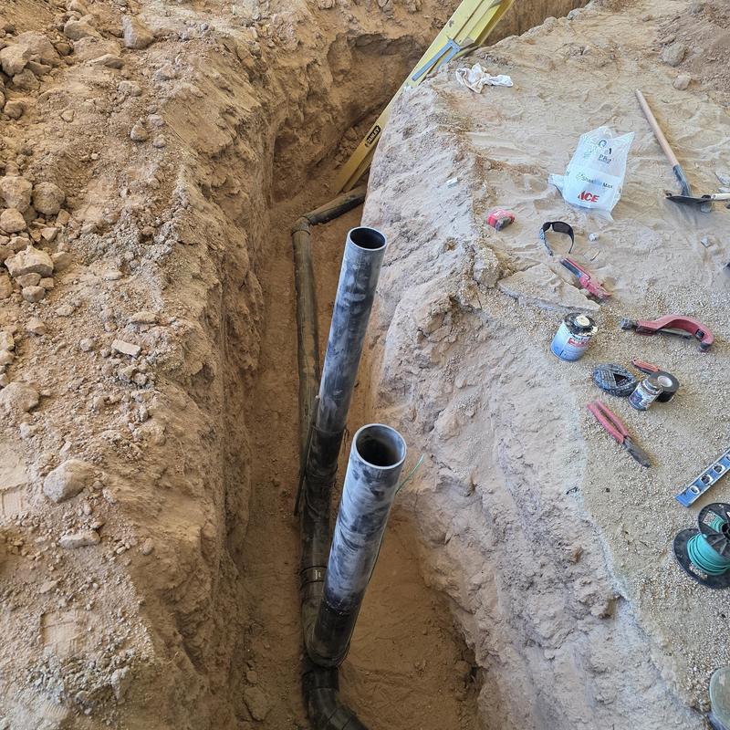 Sewer line installation trench with PVC pipes and tools Sewer line installation trench with PVC pipes and tools