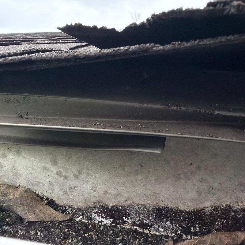 Damaged roof flashing and shingles with debris buildup