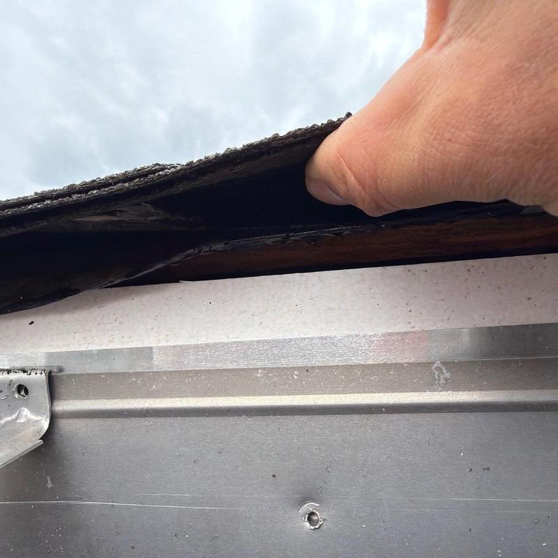 Roof shingle lifting showing possible damage above fascia trim