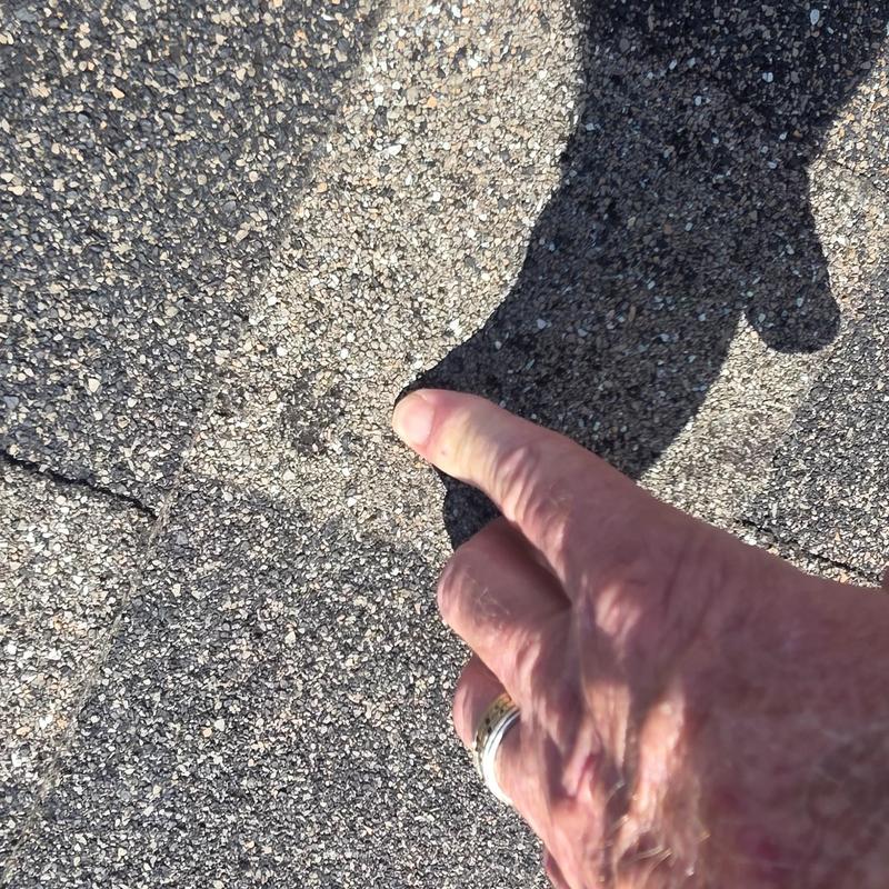 Roof shingles with hail damage being inspected