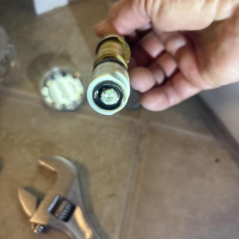 Mixit shower cartridge held by hand with wrench nearby Mixit shower cartridge held by hand with wrench nearby