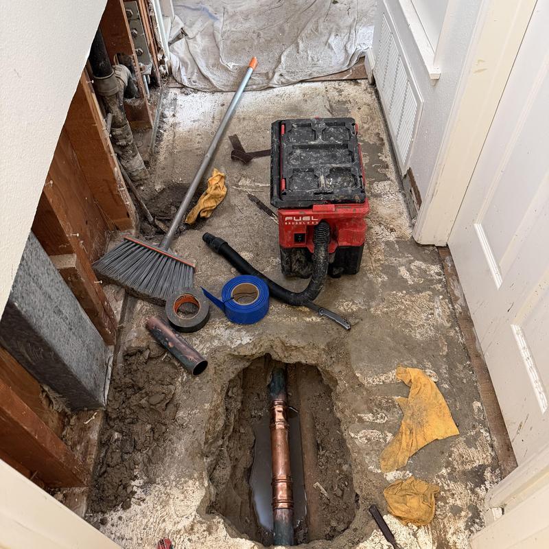 Copper slab leak pipe exposed with repair tools Copper slab leak pipe exposed with repair tools