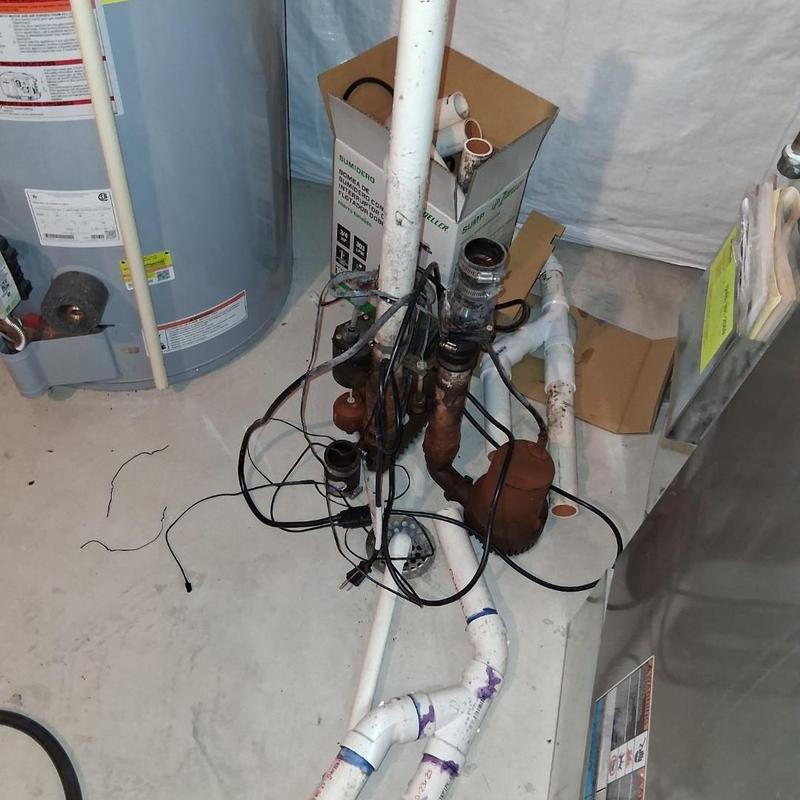 Sump pump and piping setup in basement corner