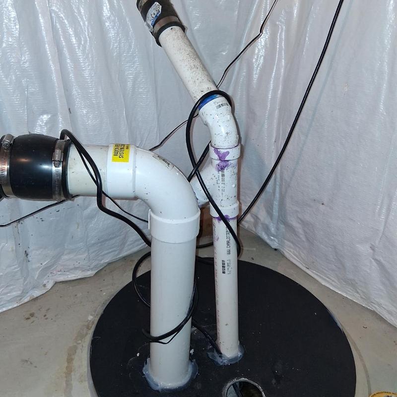 Sump pump discharge pipes with wiring in basement
