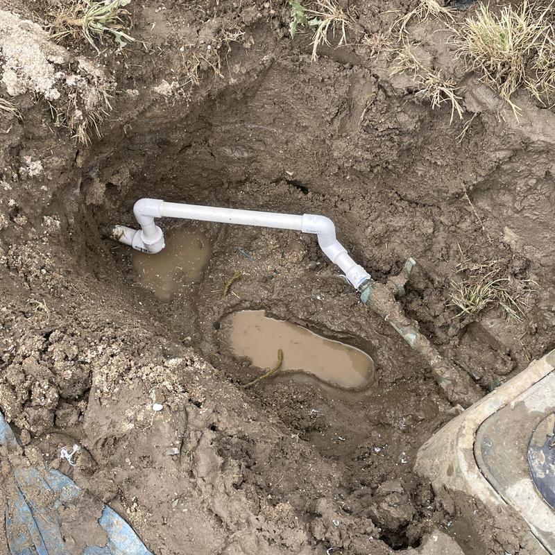 PVC pipe plumbing repair with compound-welded fittings in dirt