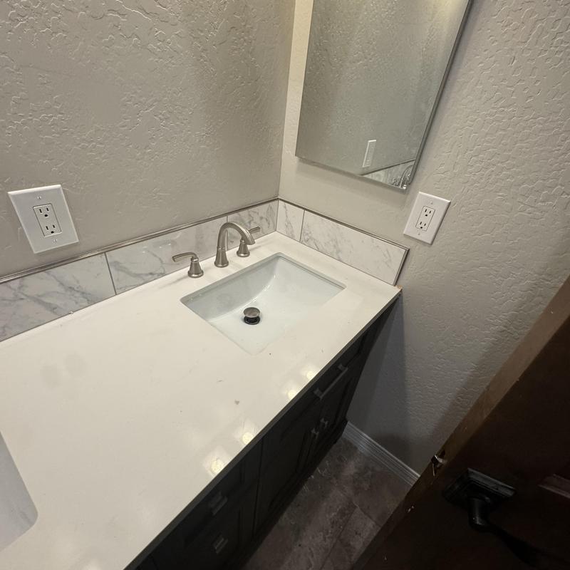 Bathroom sink with quartz countertop and marble backsplash