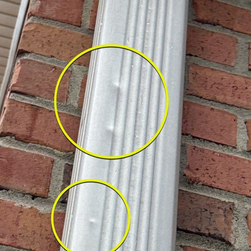 Metal flashing with hail damage dents on brick wall