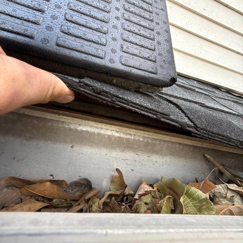 Roof shingles lifted for gutter debris inspection
