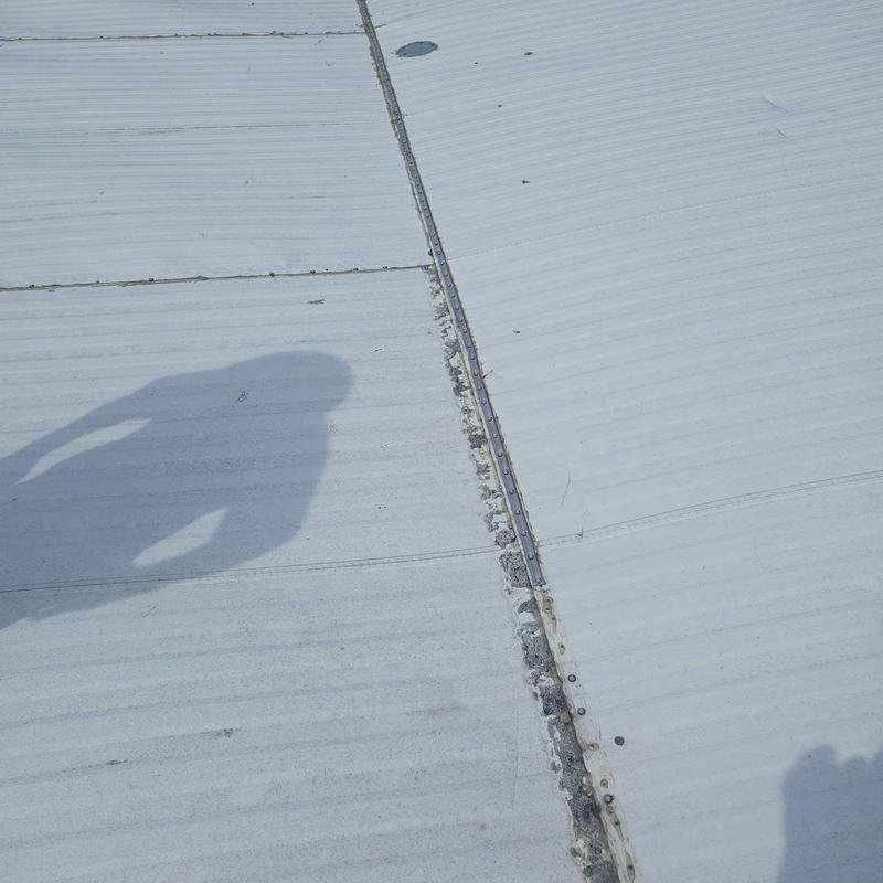 Metal roof panel seam with corrosion and wear signs