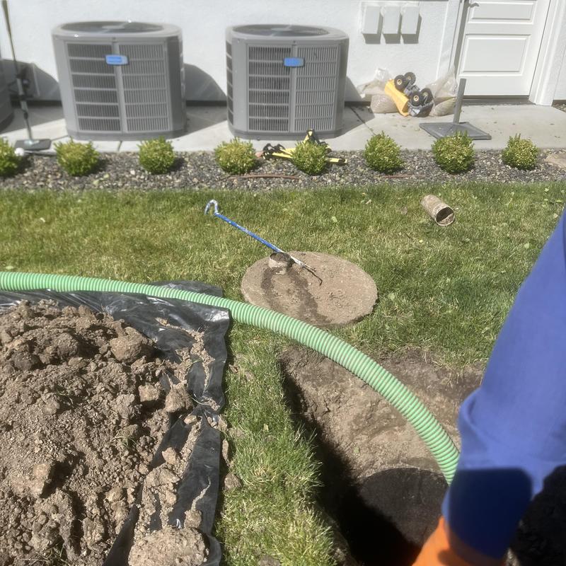 Septic tank pump out with green discharge hose near house
