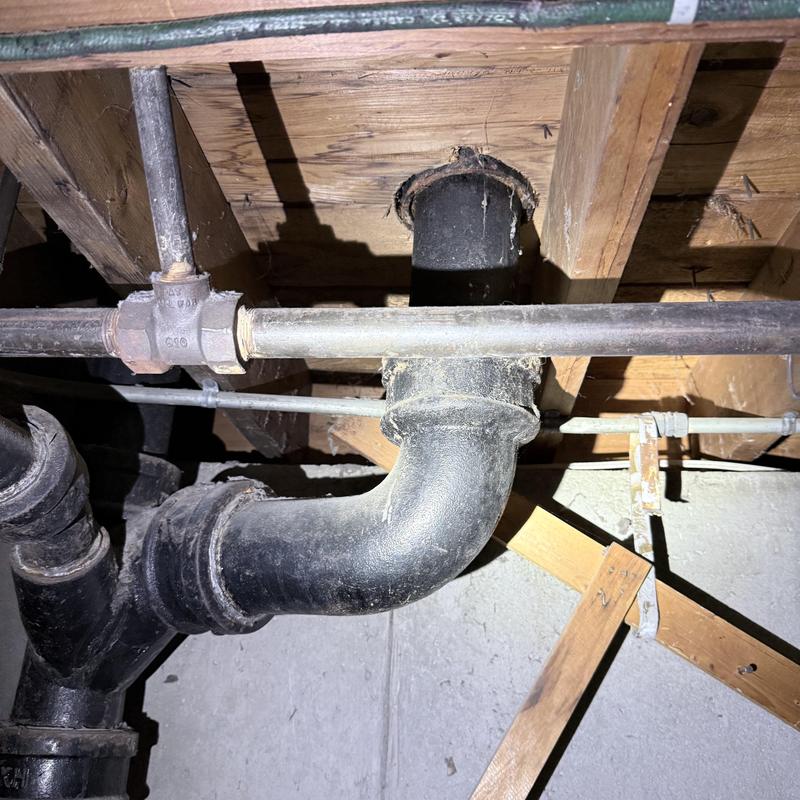 Cast iron drain pipe under floor joists with wood framing