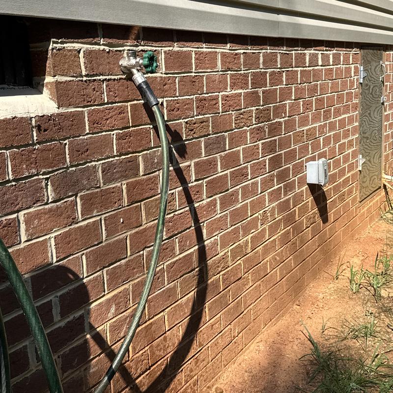 Frost proof hose bib with attached garden hose on brick wall Frost proof hose bib with attached garden hose on brick wall
