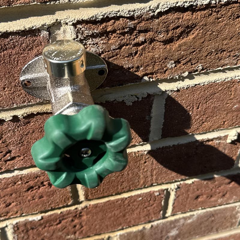 Frost proof hose bib with green handle on brick wall Frost proof hose bib with green handle on brick wall