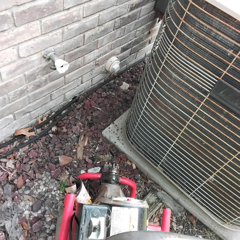 Air conditioner coil beside sewer machine on ground outdoors