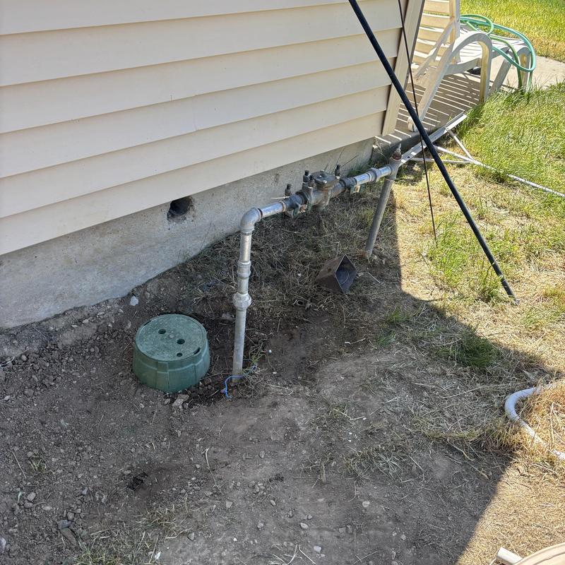 Irrigation valve and backflow assembly near house exterior