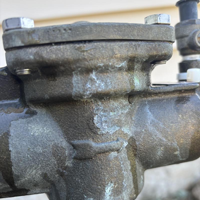 Irrigation backflow valve with visible corrosion and leak