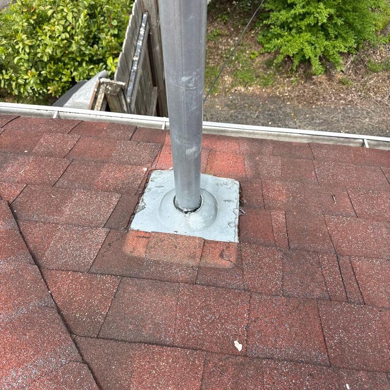 Pipe boot flashing on residential roof with red shingles