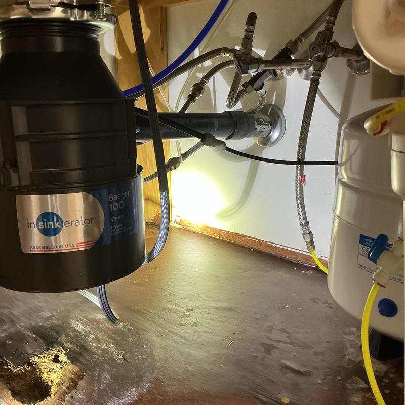 Garbage disposal with exposed drain pipe and plumbing lines