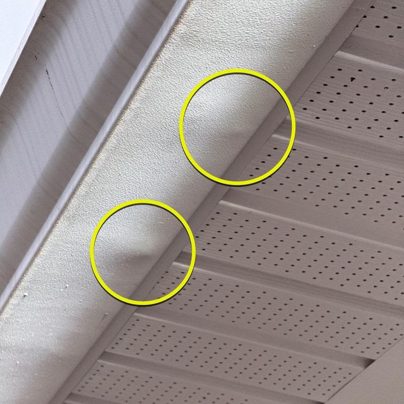 Roof soffit with hail damage dents circled in yellow