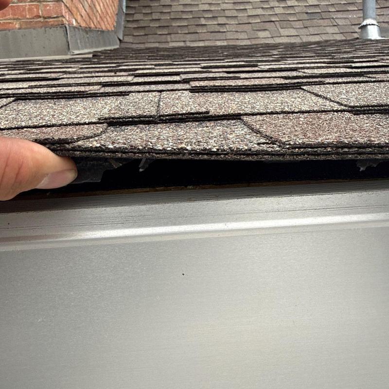 Shingle roofing lifted for damage inspection on edge