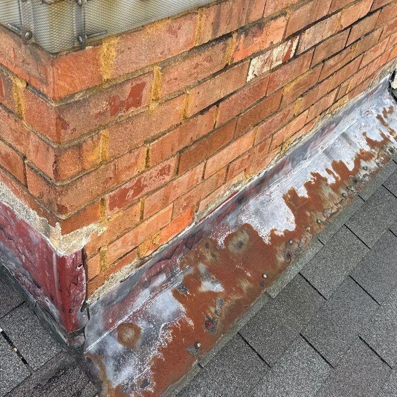 Flashing metal with rust and corrosion near brick chimney