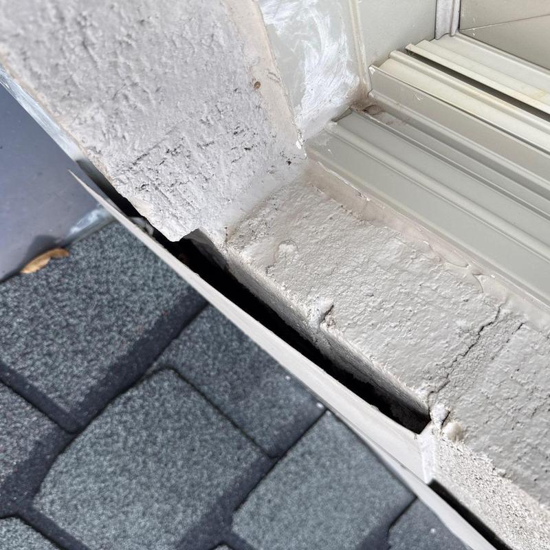 Roof flashing gap and damaged paint near shingles