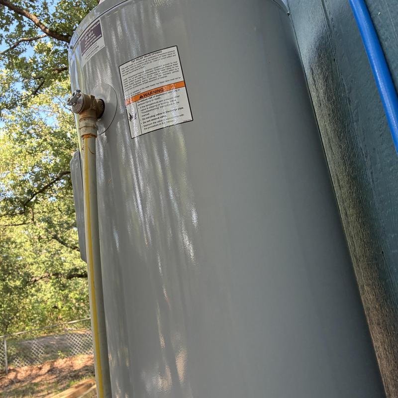 Water heater tank side view with warning labels outdoors