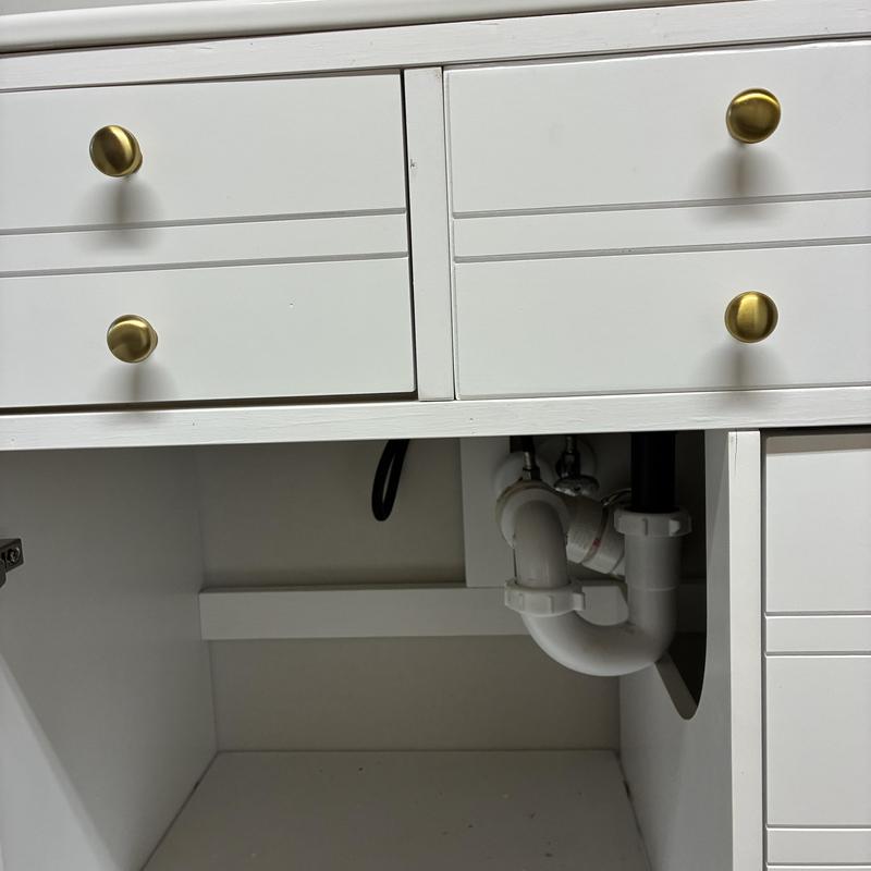 Under-sink P-trap and drain pipe installation in white cabinet