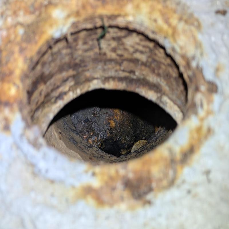 Cast iron drain pipe interior showing corrosion and buildup Cast iron drain pipe interior showing corrosion and buildup
