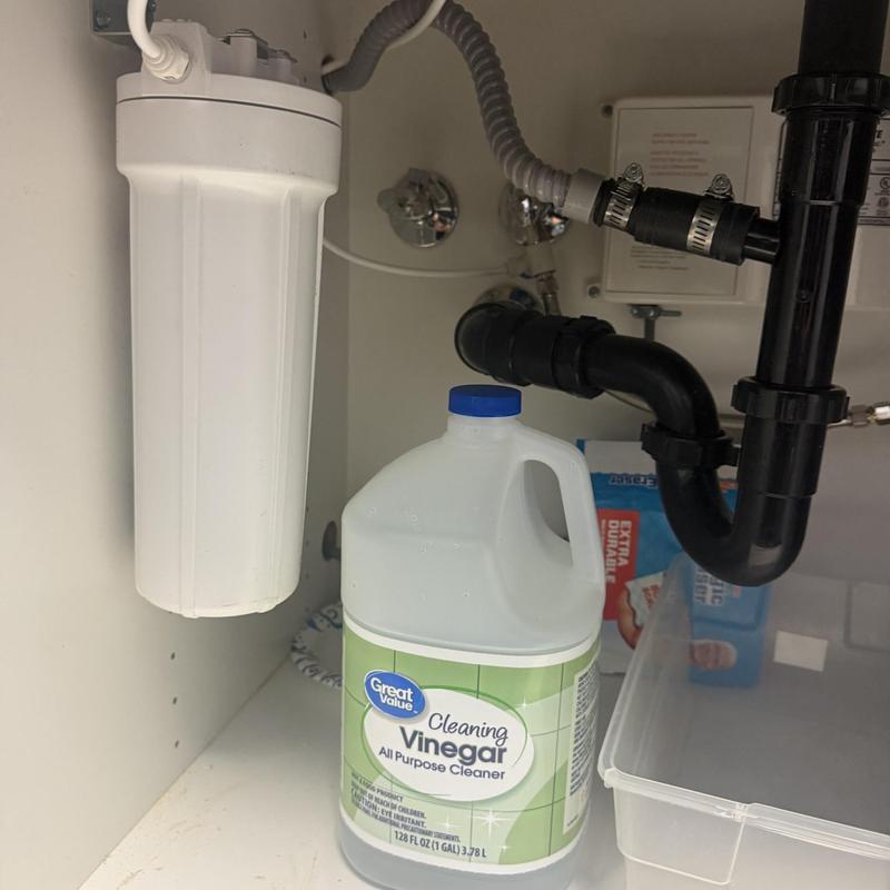 Carbon filter installation under sink with plumbing pipes
