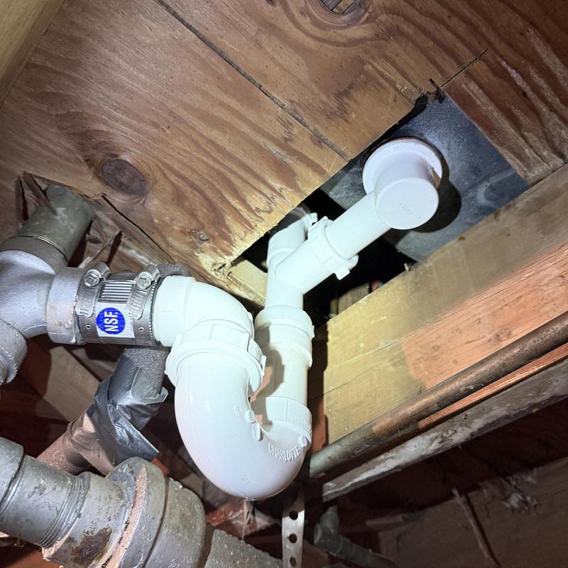PVC drain pipe assembly under wooden floor joists