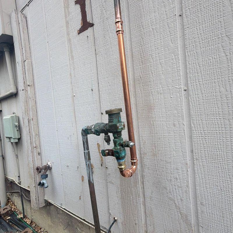 Vacuum breaker line with copper pipe repair on exterior wall