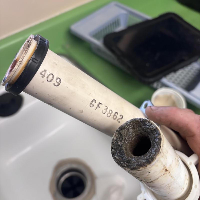 PVC drain pipe clog buildup close-up under sink