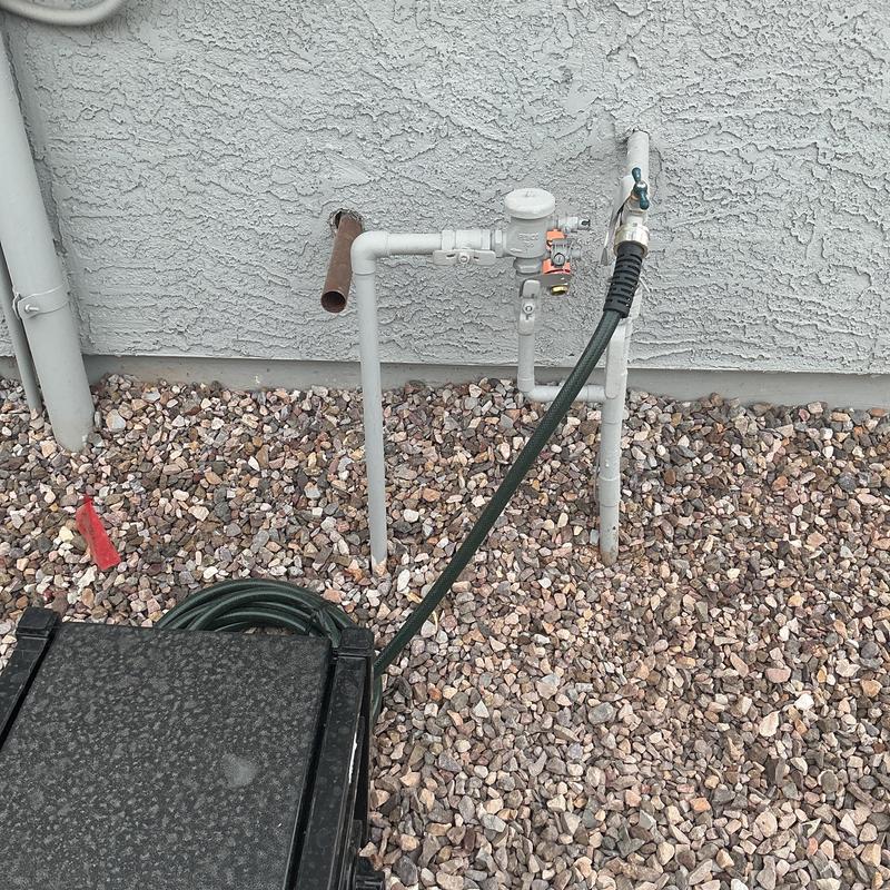 Main water service line with attached garden hose in gravel