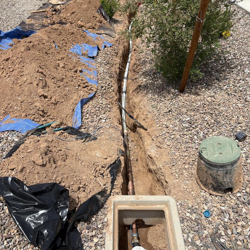 Main water service line exposed in trench with valve box