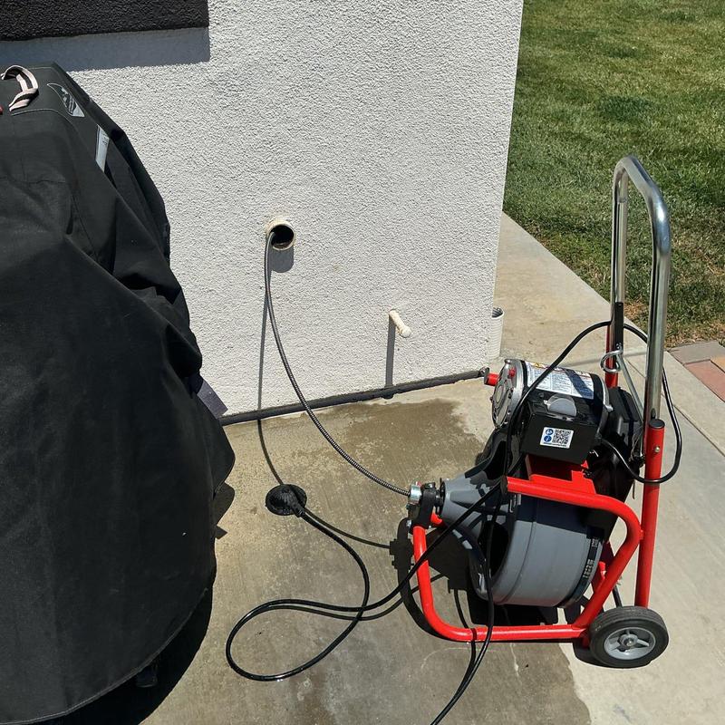 Drain line cleaning machine with snake cable on wall