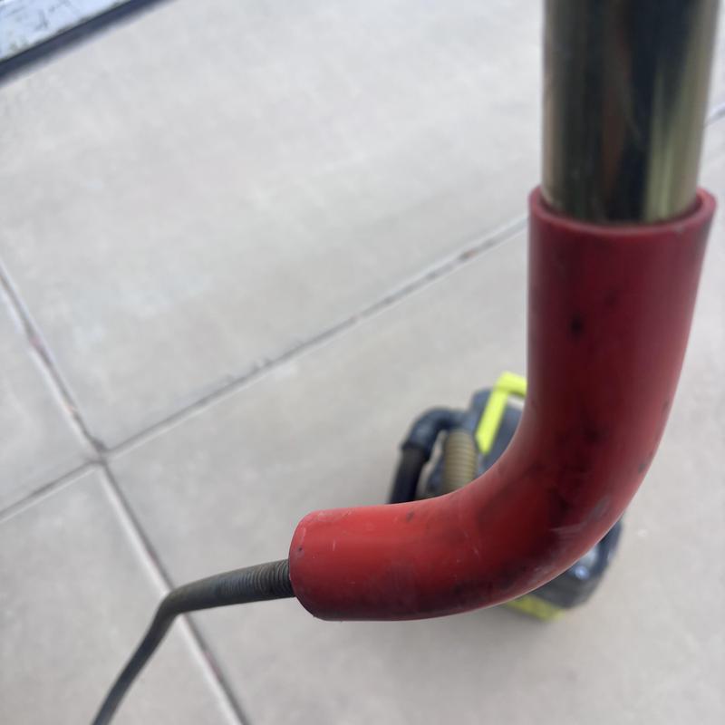 Toilet auger with red handle against concrete background