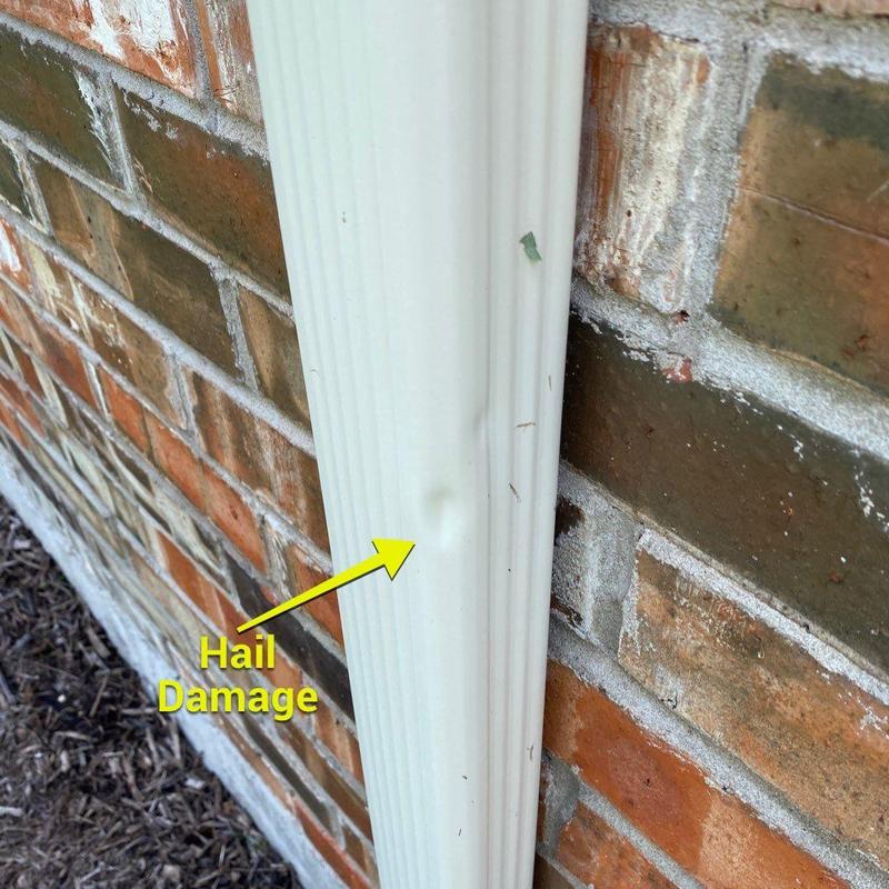 Gutter with hail damage on brick wall background