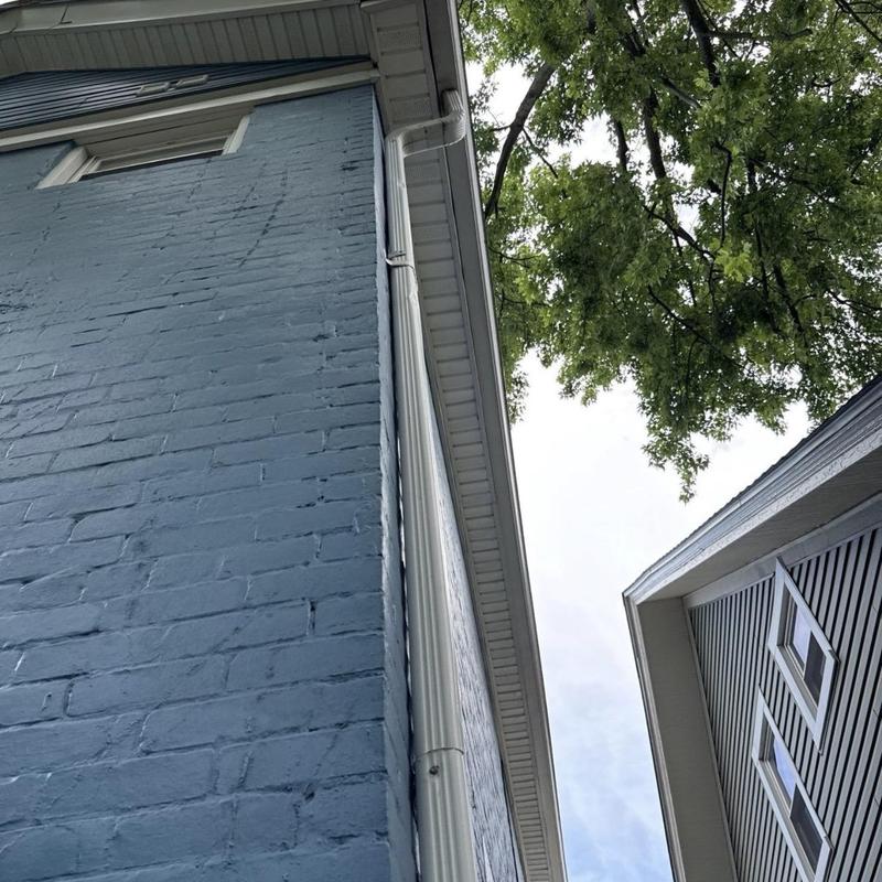 Seamless aluminum gutter downspout on blue brick wall Seamless aluminum gutter downspout on blue brick wall