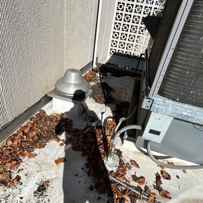 Roof drain and HVAC unit on flat roof with debris