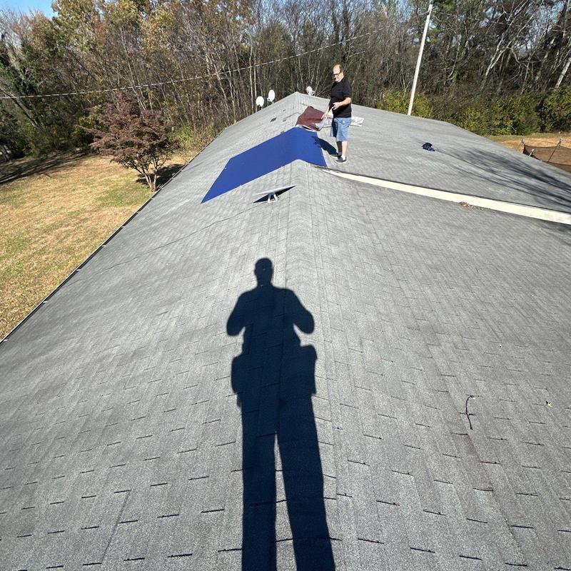 Asphalt shingle roof with ridge cap inspection and man