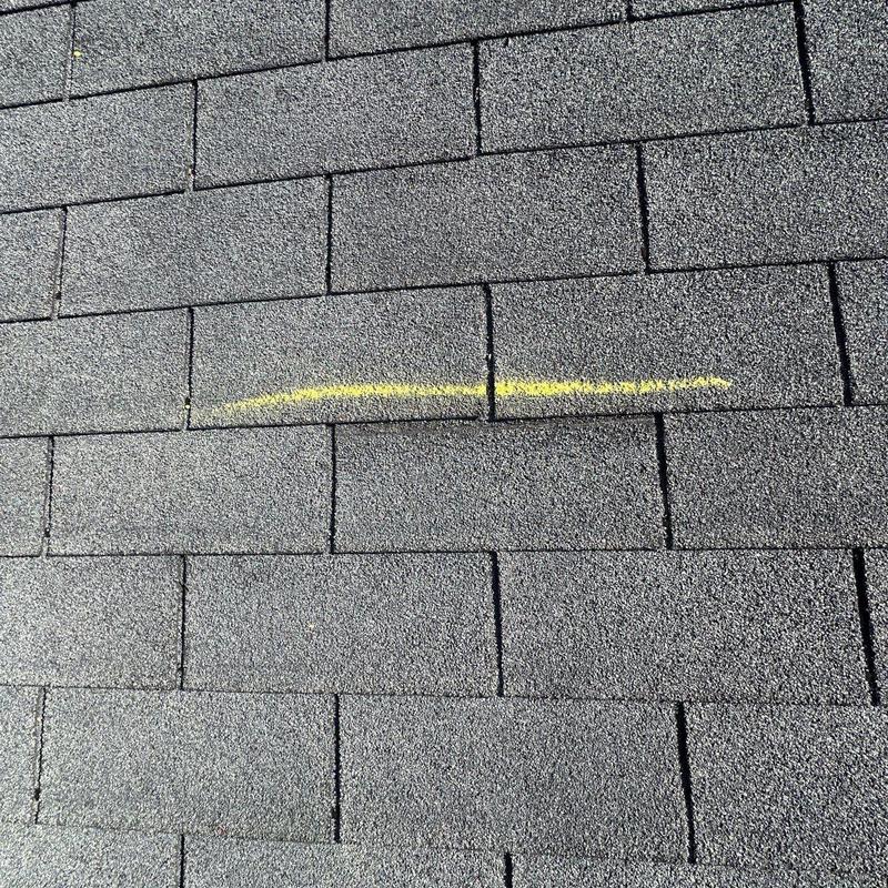 Asphalt shingles with hail damage marked in yellow