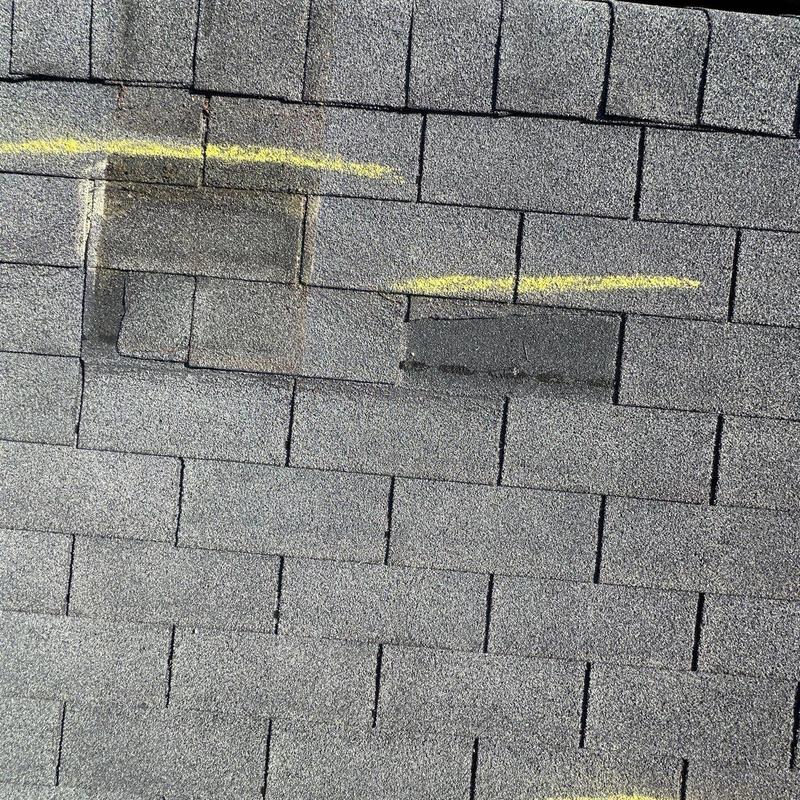 Asphalt shingles with hail damage marked for repair