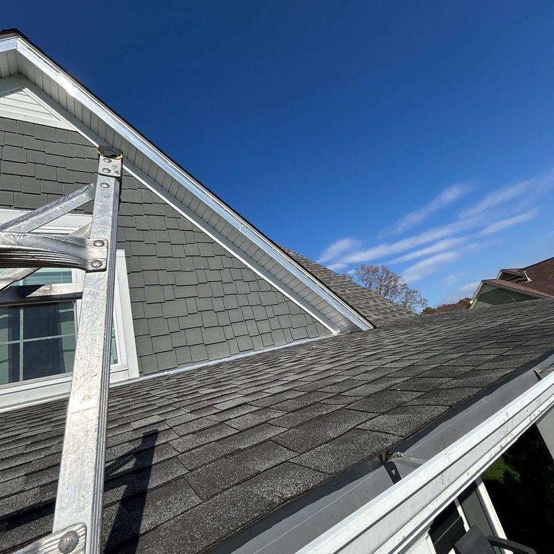 Asphalt shingle roof with ladder under clear sky