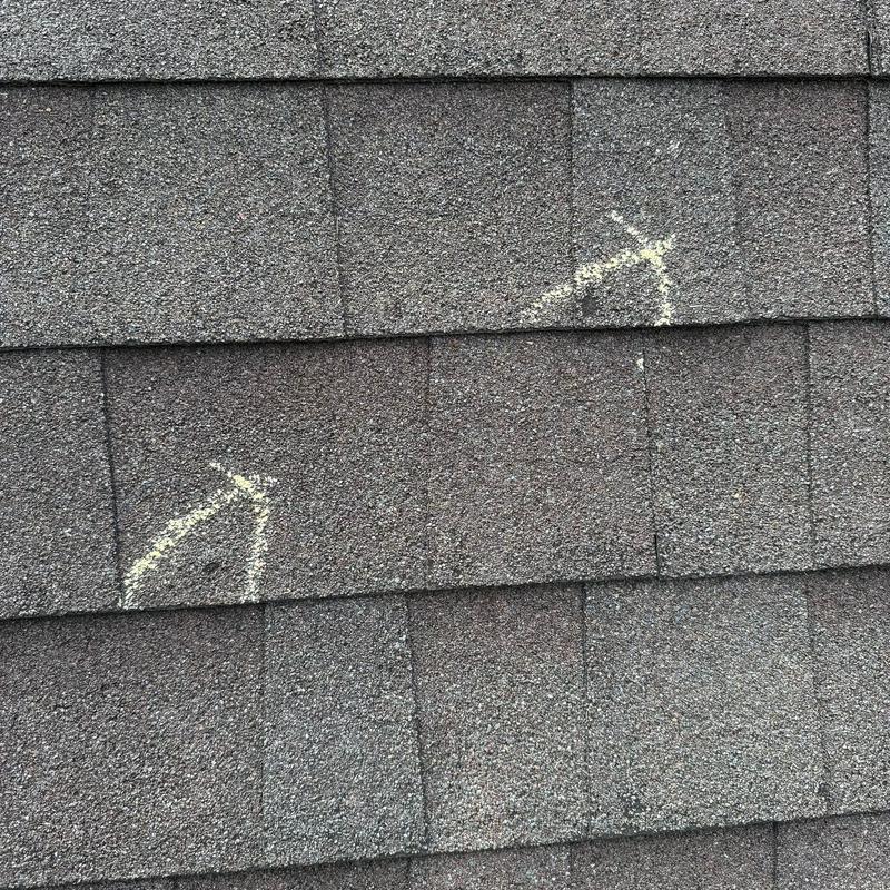 Asphalt shingles with hail damage markings on roof