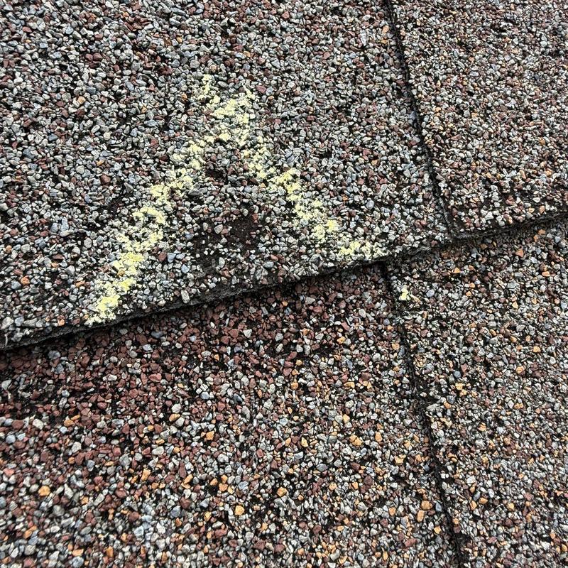 Asphalt shingles with hail damage marked for repair